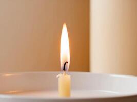 A single candle is lit in a white bowl photo