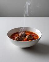 A bowl of soup with meatballs and carrots photo