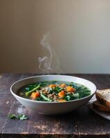 A bowl of soup with vegetables and bread on a wooden table photo