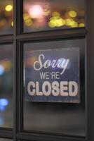 A Closed Sign Hanging on a Door Surrounded by a Warm and Inviting Ambient Background photo