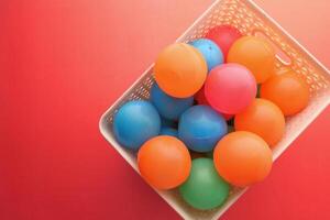 A collection of colorful balls placed in a basket set against a vibrant red background photo