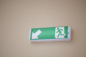 An Illuminated Emergency Exit Sign featuring a Left Arrow positioned in a Hallway setting photo