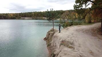 Man standing on shore. Aerial view of man standing on lake shore and taking photo of nature video