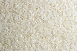 Dry Uncooked White Rice Background - Top View, Flat Lay. Scattered Raw Long Grain Rice. Asian Cuisine and Culture. Healthy Eating Ingredients. Diet Food photo