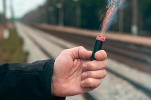 The Firecracker in a Hand. Man Holding a Burning Petard in His Hand. A Human with a Pyrotechnics that Burns with Sparks and Smoke Outdoors photo