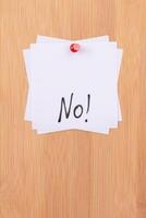 NO - White Sticky Notes with Written Word NO, Pinned to the Wooden Message Board. To Do List Reminder in the Office. Memo Note at Work photo