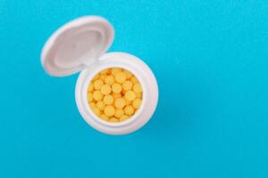 Global Pharmaceutical Industry and Medicinal Products - Yellow Vitamins or Pills in Bottle Lying on Blue Background. Copy Space, Top View, Flat Lay photo