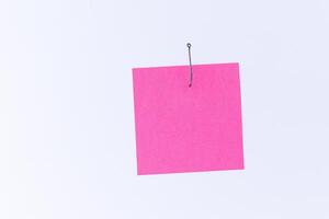 Mockup of a Blank Pink Memo Paper with Copy Space Hanging on a Fishing Hook Against the White Background. Reminder or To Do List. Sticky Note Template photo