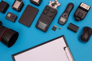 Top View of Photographer's, Videographer's or Blogger's Workplace. Digital Gadgets Lying on Blue Table - Flat Lay photo