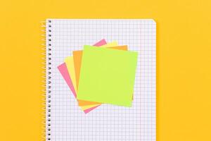 A Notepad with Sticky Notes Lying on Yellow Table - Blank Template. Top View, Flat Lay photo