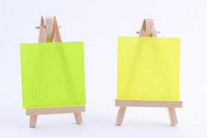Two Wooden Easels Miniature with Blank Colored Square Canvas or Memo Paper - Mockup. Mini Wooden Stand with Clean Artboard on White Background, Copy Space photo