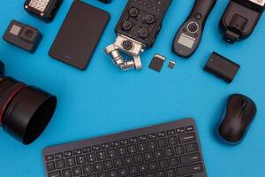 Top View of Photographer's, Videographer's or Blogger's Workplace. Digital Gadgets Lying on Blue Table - Flat Lay photo