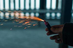 Burning Firecracker with Sparks. Guy Holding a Petard in a Hand. Loud and Dangerous New Year's Entertainment. Hooliganism with Pyrotechnics. Noise of Firecrackers in Public Places photo