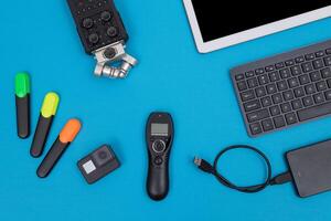 Top View of Photographer's, Videographer's or Blogger's Workplace. Digital Gadgets Lying on Blue Table - Flat Lay photo