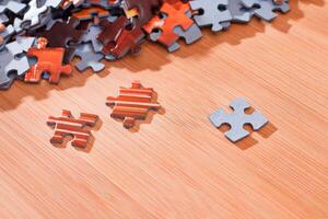 Colorful Pieces of a Mixed Jigsaw Puzzle Lie on the Wooden Table - Strategy and Solving Problem Concept photo