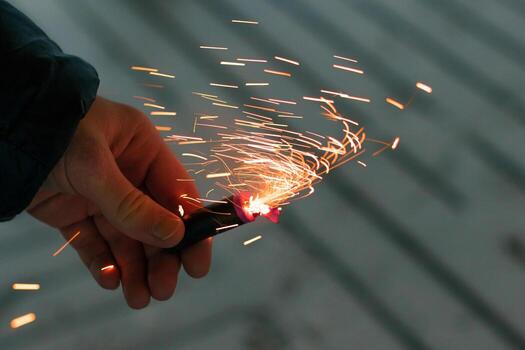 Burning Firecracker with Sparks. Guy Holding a Petard in a Hand. Loud and Dangerous New Year's Entertainment. Hooliganism with Pyrotechnics. Noise of Firecrackers in Public Places photo