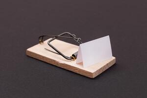 Blank White Sheet of Paper in Wooden Mousetrap - Template. Small Memo Paper in Mouse Trap on Black Background photo