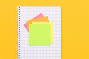 A Notepad with Sticky Notes Lying on Yellow Table - Blank Template. Top View, Flat Lay photo