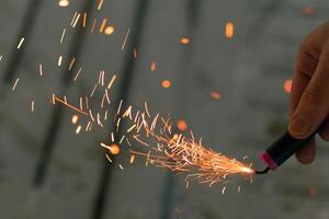 Burning Firecracker with Sparks. Guy Holding a Petard in a Hand. Loud and Dangerous New Year's Entertainment. Hooliganism with Pyrotechnics. Noise of Firecrackers in Public Places photo