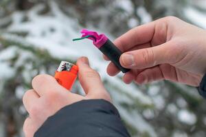 Guy Sets Fire to the Flash Noise Firecracker Outdoors in Winter at Daytime. Loud and Dangerous New Year's Entertainment. Hooliganism with Pyrotechnics. Noise of Petards in Public Places photo