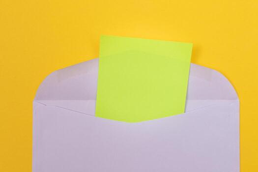 Violet Envelope with Blank Green Sheet of Paper Inside, Lying on Yellow Background - Mock Up with Copy Space. Receiving Mail or Notice, Sending Postcard - Top View, Flat Lay photo