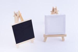 Two Wooden Easels Miniature with Blank Black and White Square Canvas for Artists and Painters - Mockup. Mini Wooden Stand with Clean Artboard on White Background, Copy Space photo