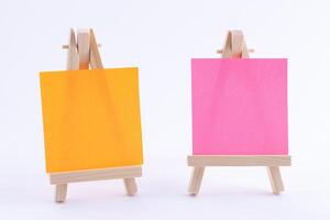 Two Wooden Easels Miniature with Blank Colored Square Canvas or Memo Paper - Mockup. Mini Wooden Stand with Clean Artboard on White Background, Copy Space photo