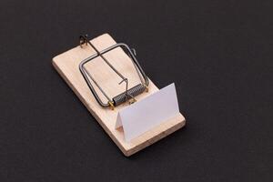 Blank White Sheet of Paper in Wooden Mousetrap - Template. Small Memo Paper in Mouse Trap on Black Background photo
