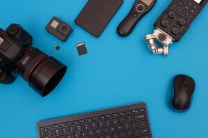 Top View of Photographer's, Videographer's or Blogger's Workplace. Digital Gadgets Lying on Blue Table - Flat Lay photo