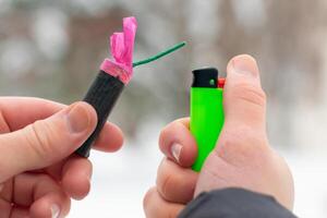 Guy Sets Fire to the Flash Noise Firecracker Outdoors in Winter at Daytime. Loud and Dangerous New Year's Entertainment. Hooliganism with Pyrotechnics. Noise of Petards in Public Places photo