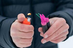 Guy Sets Fire to the Flash Noise Firecrackers Outdoors in Winter at Daytime. Loud and Dangerous New Year's Entertainment. Hooliganism with Pyrotechnics. Noise of Petards in Public Places photo