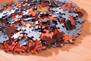 Colorful Pieces of a Mixed Jigsaw Puzzle Lie on the Wooden Table - Strategy and Solving Problem Concept photo