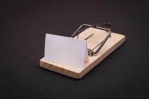 Blank White Sheet of Paper in Wooden Mousetrap - Template. Small Memo Paper in Mouse Trap on Black Background photo