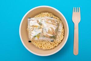 Opened Package with Uncooked Instant Noodles on Blue Background. Raw Pasta. Dry Asian Fast Food. Quick Lunch photo