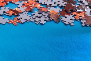 Mixed Pieces of a Colorful Jigsaw Puzzle Lie on the Blue Background With Copy Space - Strategy and Solving Problem Concept photo