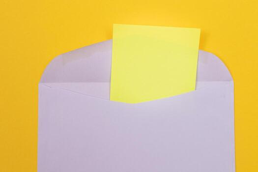 Violet Envelope with Blank Yellow Sheet of Paper Inside, Lying on Yellow Background - Mock Up with Copy Space. Receiving Mail or Notice, Sending Postcard - Top View, Flat Lay photo