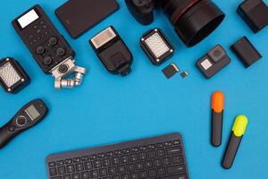 Top View of Photographer's, Videographer's or Blogger's Workplace. Digital Gadgets Lying on Blue Table - Flat Lay photo