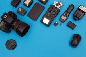 Top View of Photographer's, Videographer's or Blogger's Workplace. Digital Gadgets Lying on Blue Table - Flat Lay photo