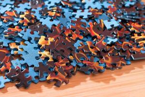Colorful Pieces of a Mixed Jigsaw Puzzle Lie on the Wooden Table - Strategy and Solving Problem Concept photo