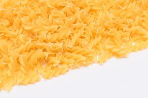Uncooked Fusilli Pasta with Copy Space on White Background. Raw and Dry Macaroni. Fat and Unhealthy Food - Flat Lay photo