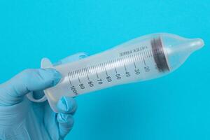 Safe Vaccine, Anti Vaccination Concept - Syringe in a Condom Holds in a Hand with Medical Glove. Mistrust of Vaccination. Natural Immunity. Skepticism About the Vaccine. Freedom and Human Rights photo