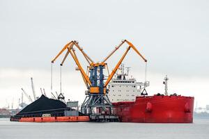Large red cargo ship loading with a coal in the port photo