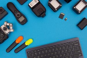 Top View of Photographer's, Videographer's or Blogger's Workplace. Digital Gadgets Lying on Blue Table - Flat Lay photo