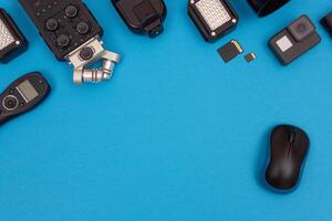 Top View of Photographer's, Videographer's or Blogger's Workplace. Digital Gadgets Lying on Blue Table - Flat Lay photo
