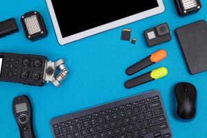 Top View of Photographer's, Videographer's or Blogger's Workplace. Digital Gadgets Lying on Blue Table - Flat Lay photo