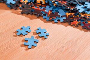 Colorful Pieces of a Mixed Jigsaw Puzzle Lie on the Wooden Table - Strategy and Solving Problem Concept photo