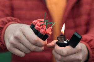 Man in Red Jacked Lighting Up Several Firecrackers in his Hand Using Gasoline Lighter. Guy Getting Ready for New Year Fun with Fireworks or Pyrotechnic Products photo