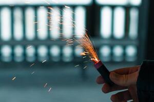 Burning Firecracker with Sparks. Guy Holding a Petard in a Hand. Loud and Dangerous New Year's Entertainment. Hooliganism with Pyrotechnics. Noise of Firecrackers in Public Places photo