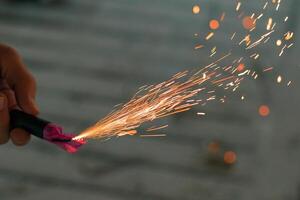 Burning Firecracker with Sparks. Guy Holding a Petard in a Hand. Loud and Dangerous New Year's Entertainment. Hooliganism with Pyrotechnics. Noise of Firecrackers in Public Places photo