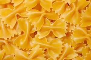 Uncooked Farfalle Pasta. A Culinary Canvas of Bow-Tie Macaroni, Creating a Lively and Textured Background for Gourmet Cooking. Dry Pasta. Raw Macaroni - Top View, Flat Lay photo